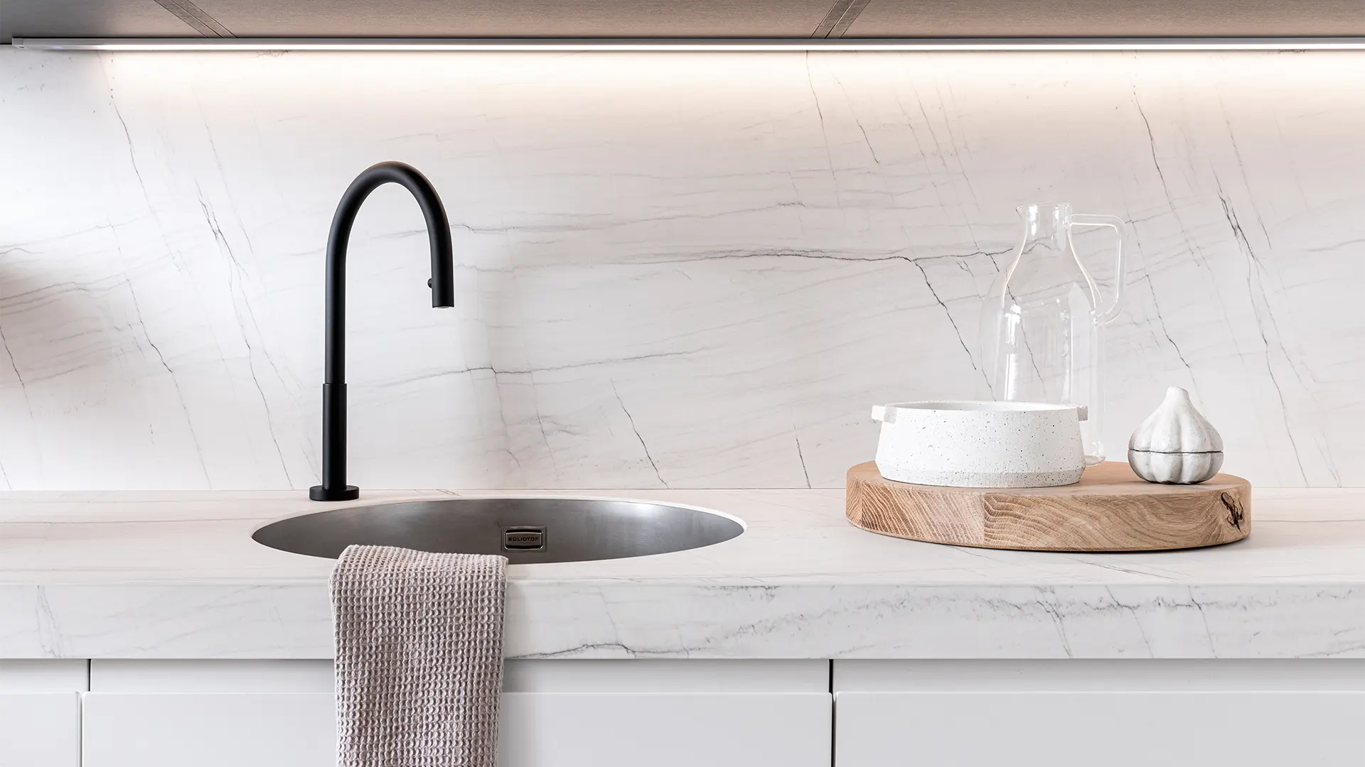 Piano cucina in HPL effetto marmo bianco con vasca tonda integrata e rubinetto nero opaco