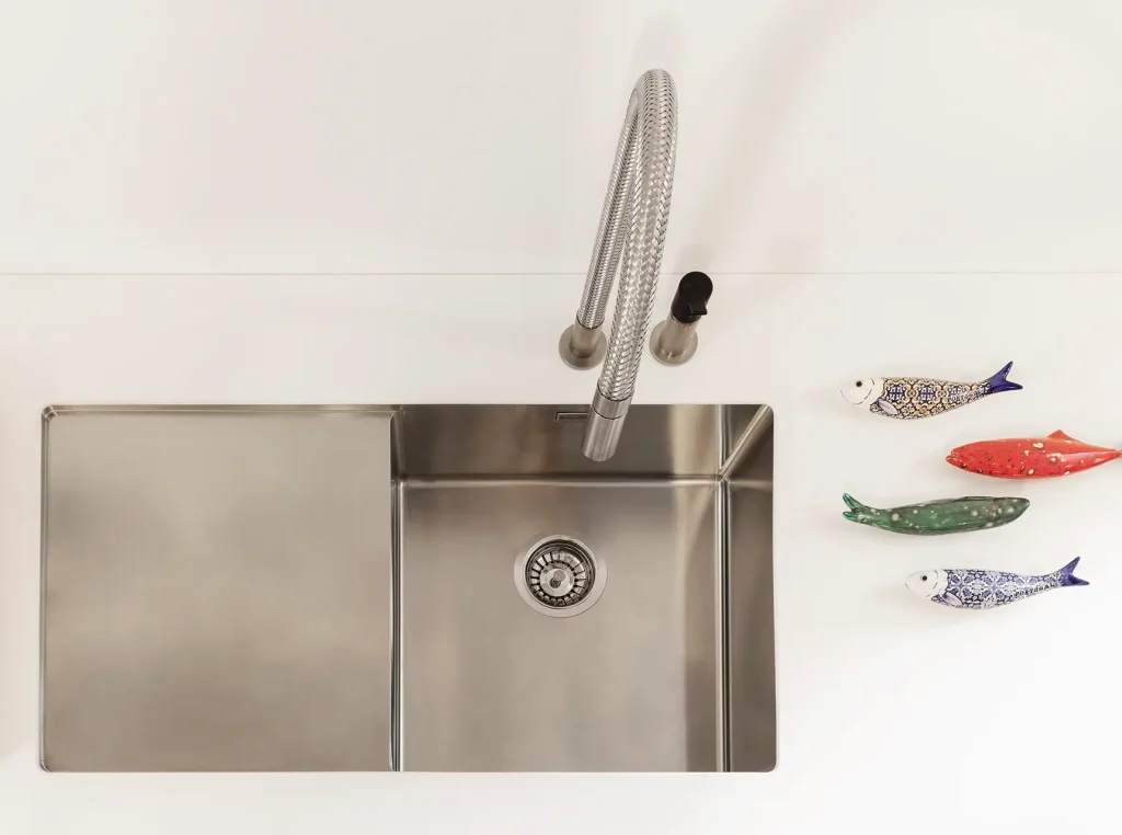 Vasca integrata in acciaio inox con sgocciolatoio e miscelatore flessibile su piano cucina bianco